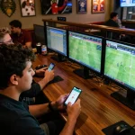 Sports betting excitement with real-time kết quả bóng đá visible on screens, creating a lively atmosphere