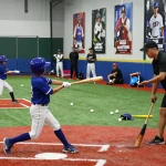 Young athletes at hitclub practicing baseball hitting techniques in a vibrant training facility.