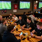Fans engaging in sports betting at lively sports bar during a footballl game.